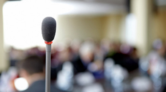 A microphone, with blurred crowd in background.